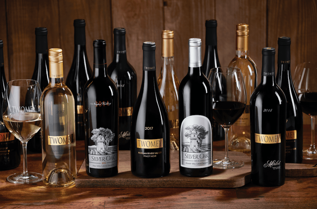 Assortment of Silver Oak and Twomey wines displayed with red and white wine glasses on a rustic wooden surface.